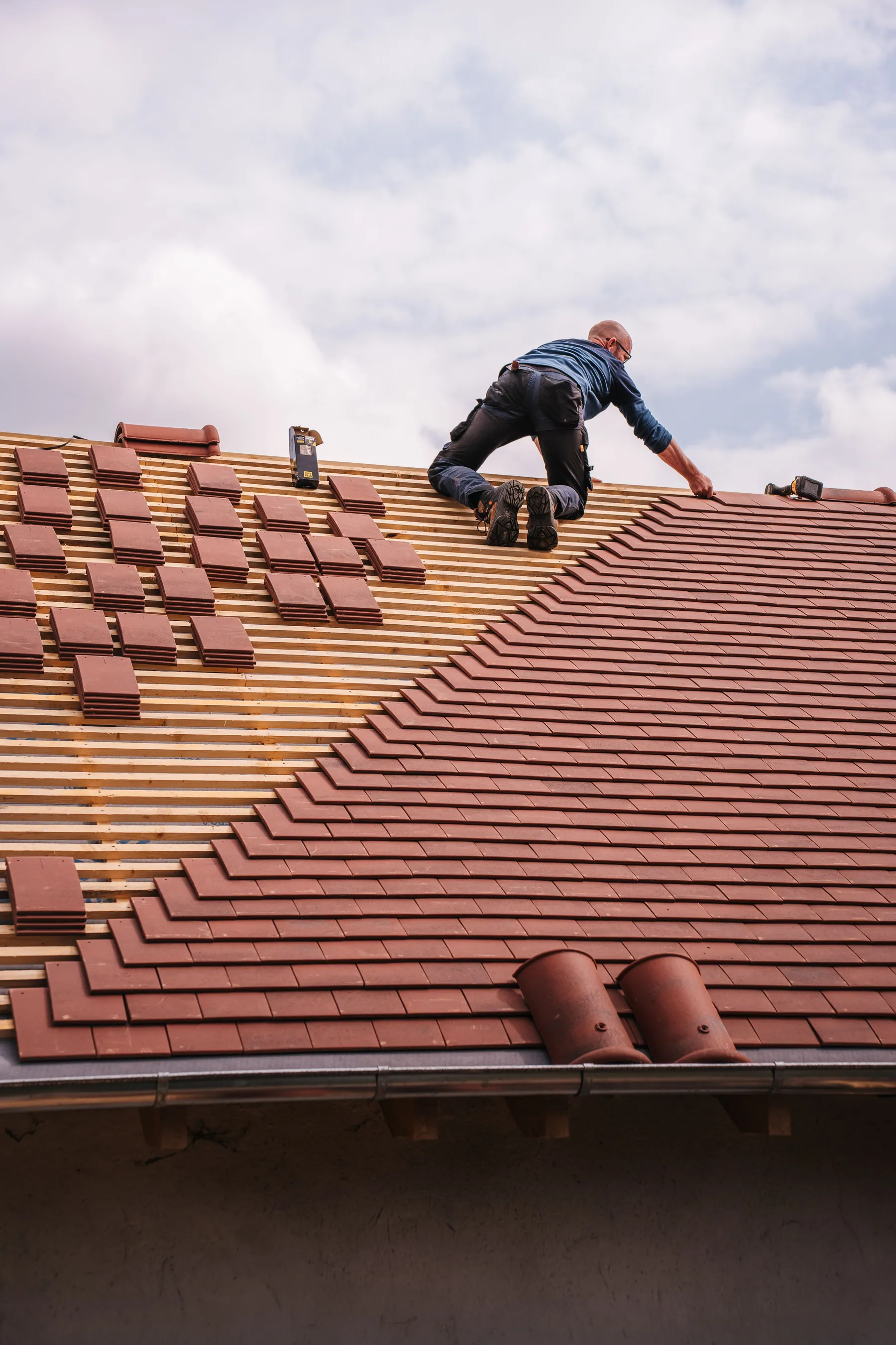 Professional roofer installing tiles onto measured roof battens